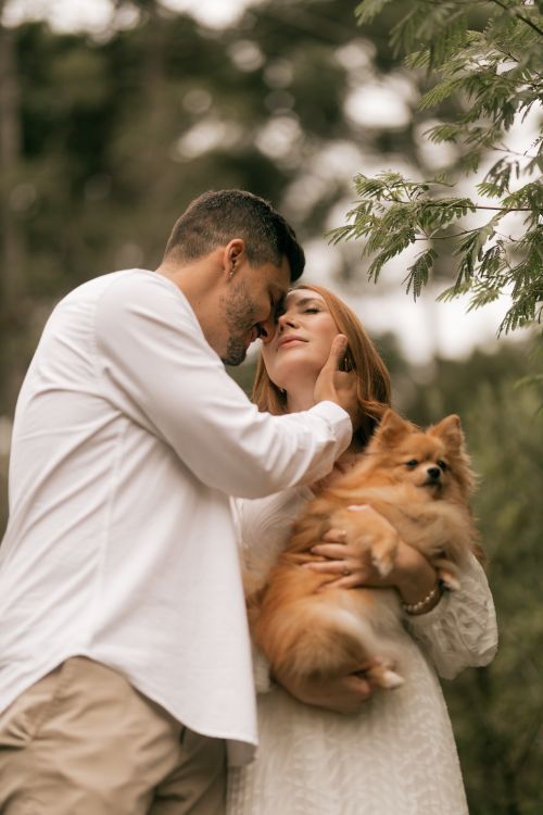 Free Loving couple embracing with their Pomeranian in a natural setting. Stock Photo