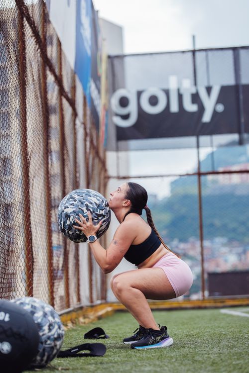 Free Athletic woman doing squats with a medicine ball on a sports field. Stock Photo
