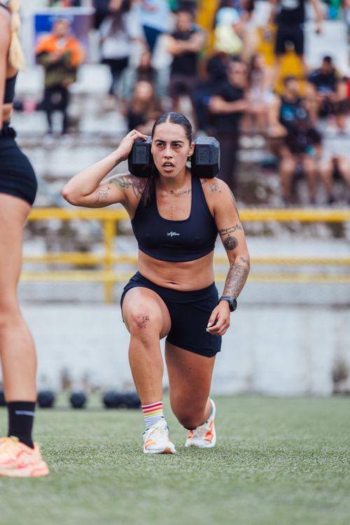 Free Young female athlete performing weighted lunges on a sports field, showcasing strength and determination. Stock Photo