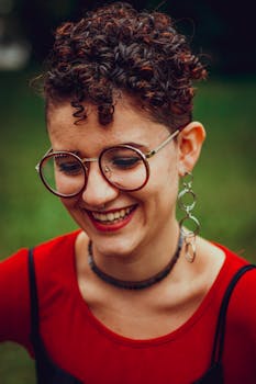 一个戴着眼镜和耳环、留着短卷发的快乐女人在户外微笑