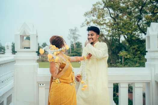 Couple in traditional attire sharing a joyful moment in a South Asian pre-wedding ceremony.