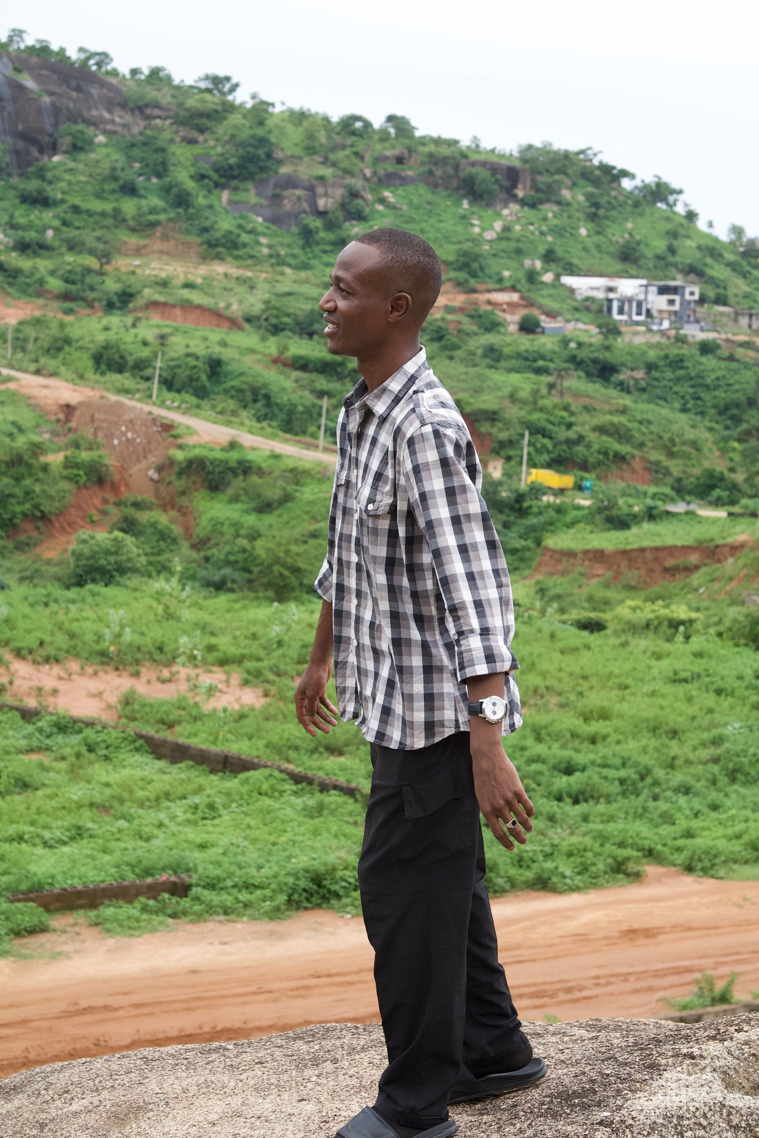 Young Nigerian man in casual wear exploring the scenic Mpape Hills near Abuja.