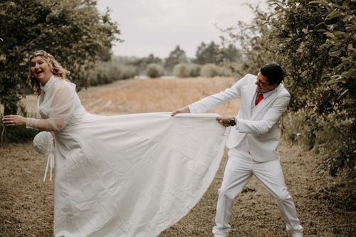 Free A joyful bride and groom share a playful moment outdoors in a wedding setting. Stock Photo