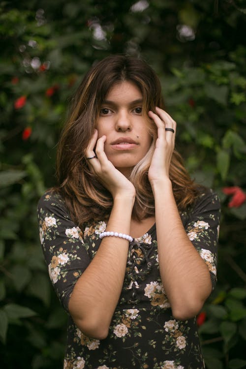 Donna In Camicia Floreale, Toccando Il Suo Viso Con Le Mani