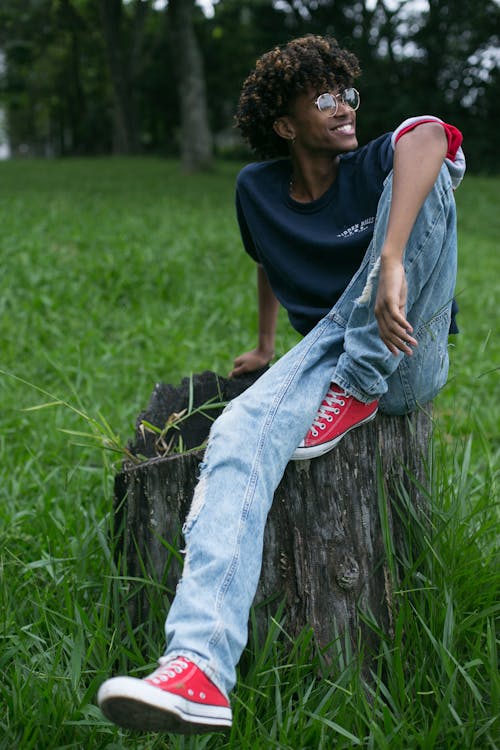Man in Blue Crew Neck T-shirt and Blue Denim Jeans Sitting on Tree Log