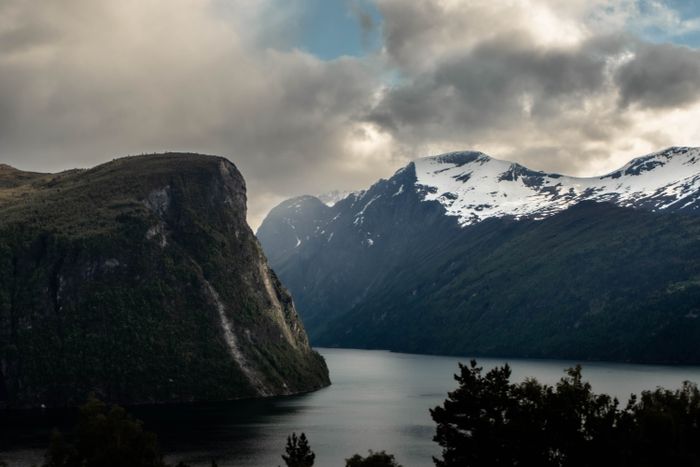 Breathtaking view of a Norwegian fjord surrounded by lush cliffs and snow-capped mountains, by Thea Cintia Paixão da Silva on Pexels