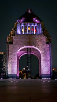 Nighttime view of a lit-up monument in Mexico City with vivid colors.
