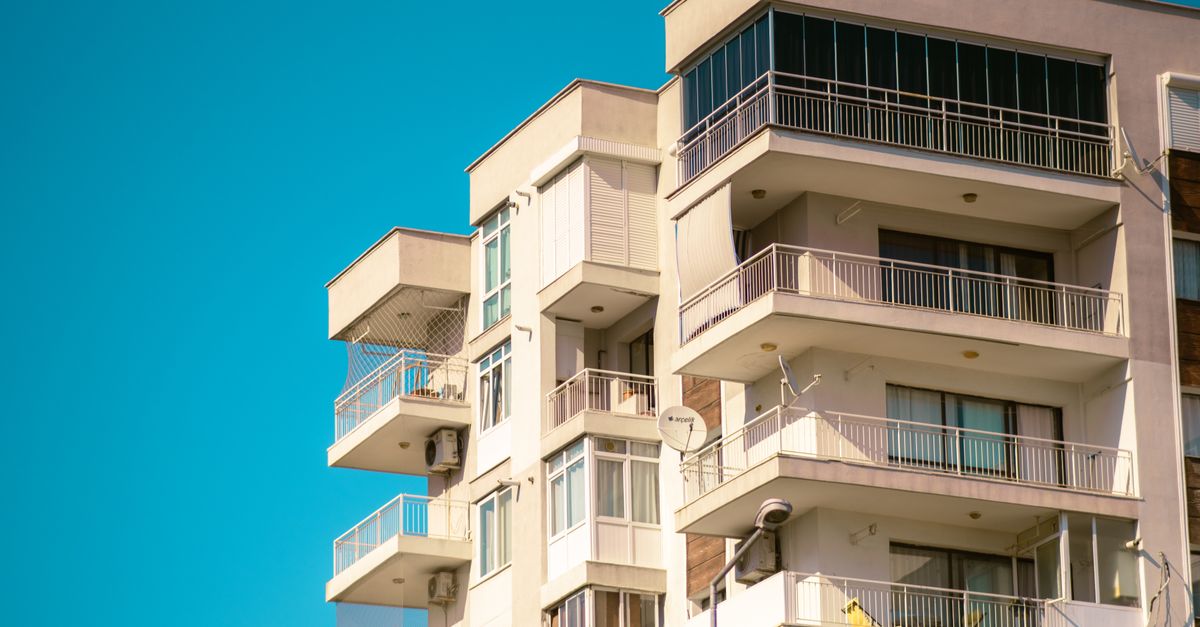 A modern apartment building with balconies in İzmir, Türkiye, under clear blue skies.