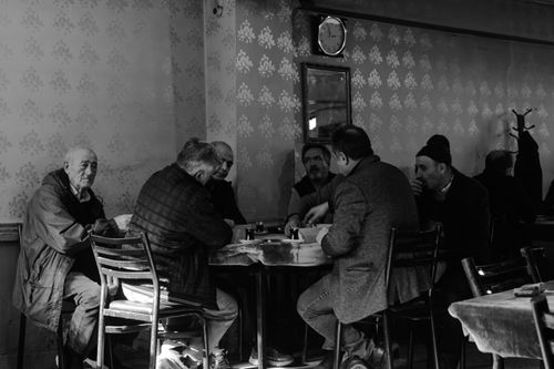 Free A group of senior men engage in a card game inside a warmly lit, vintage-style cafe. Stock Photo