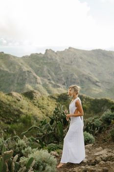 A serene scene of a woman walking in a Greek mountain landscape with cacti.