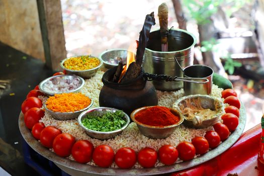 A vibrant display of Indian culinary ingredients and spices on a round platter for a traditional ritual.