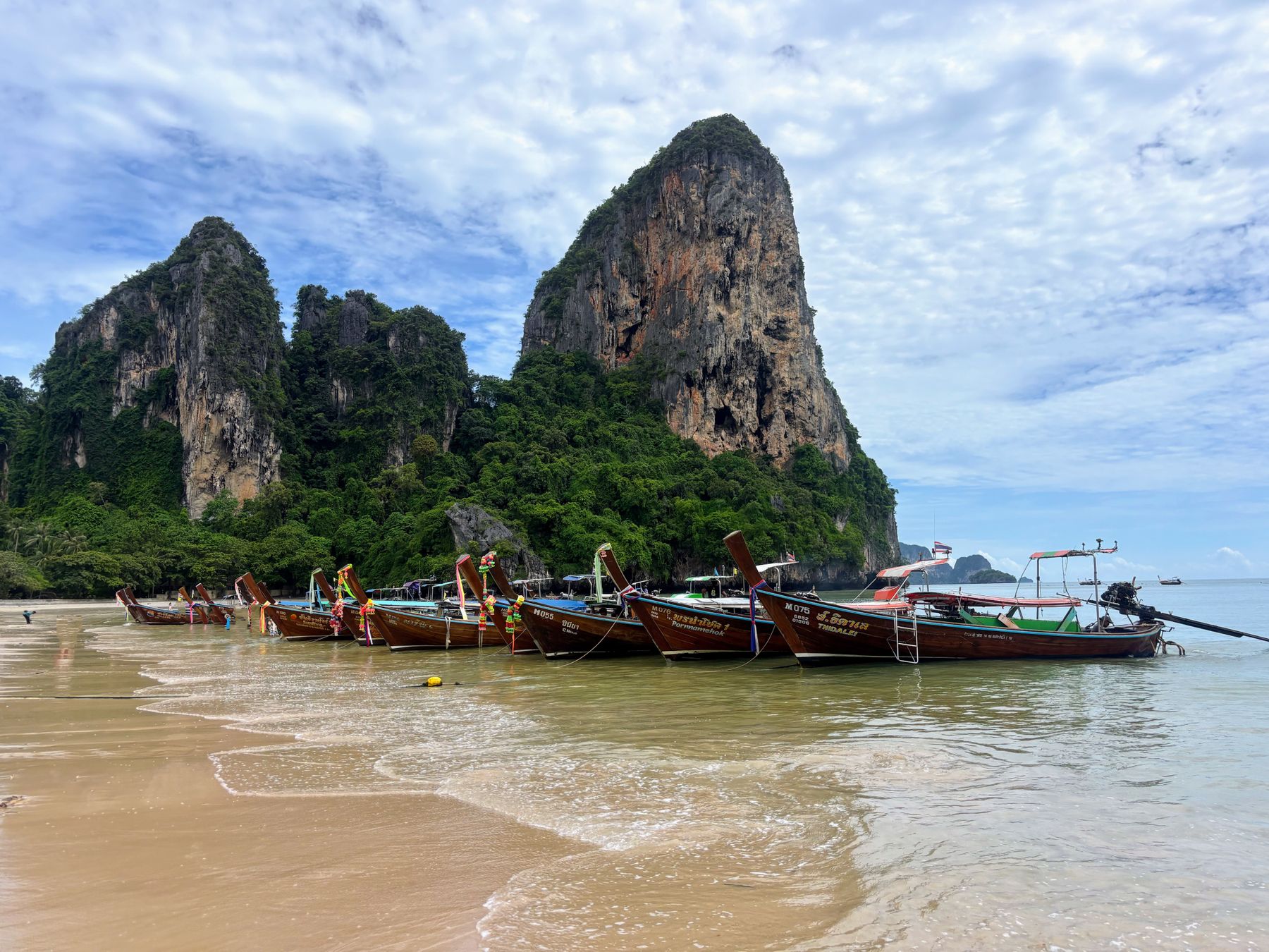 Longtail boats along Railay Beach beneath Krabi's limestone cliffs