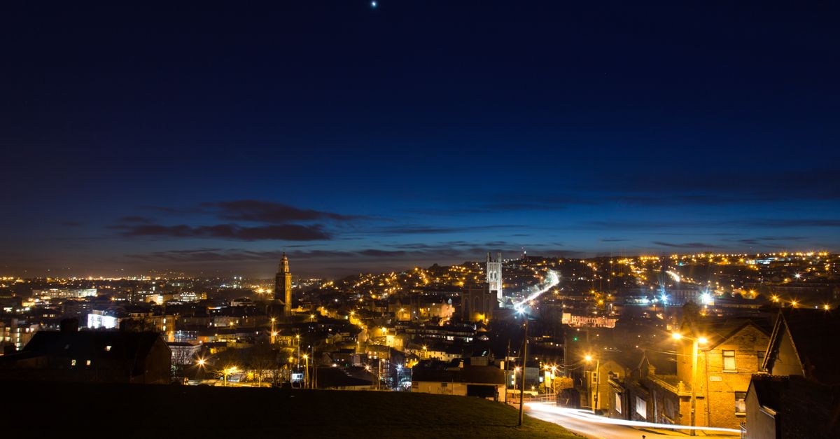 Stunning view of Cork, Ireland at twilight, showcasing city lights and a starry sky.