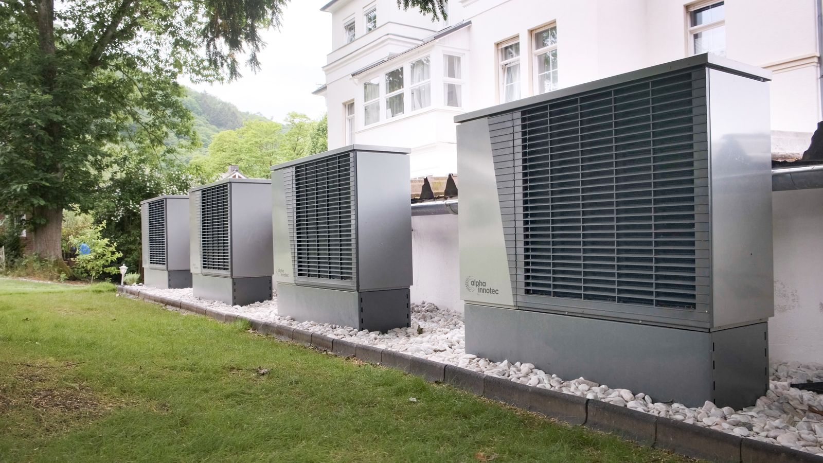 A row of large grey heat pump units installed outside a white house — How much does an AC repair cost in Miami? — Still Blazin, Miami