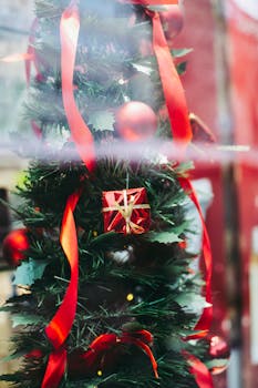 透过美丽的圣诞装饰玻璃，可以看到舒适的商店里，针叶树树枝上挂着红球