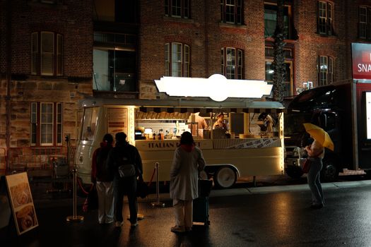 A cozy Italian food truck in Sydney serves customers at night, offering a taste of urban culinary culture.