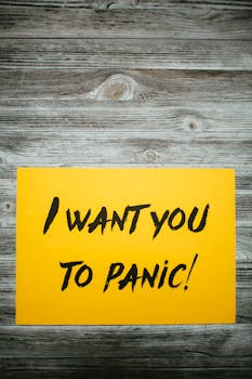 木桌上放着一张黄色纸，从上方看去，上面刻着“我想让你惊慌失措”的铭文