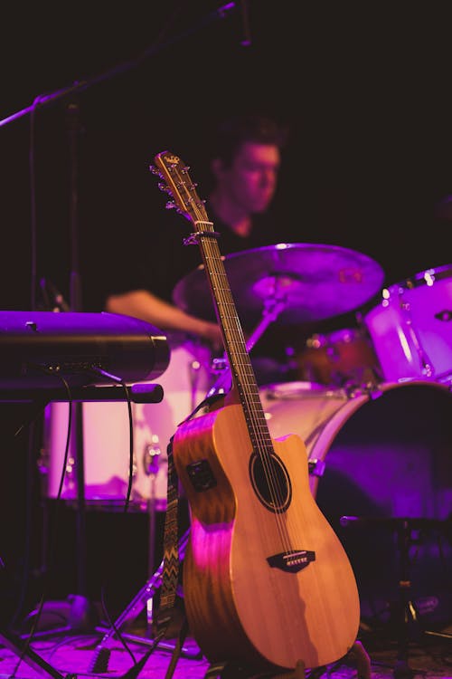 Musician playing drums on stage near guitar