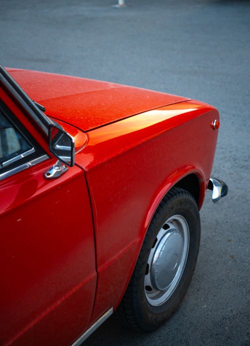 Free A vibrant red vintage car parked on a gray asphalt surface, showcasing its timeless design. Stock Photo