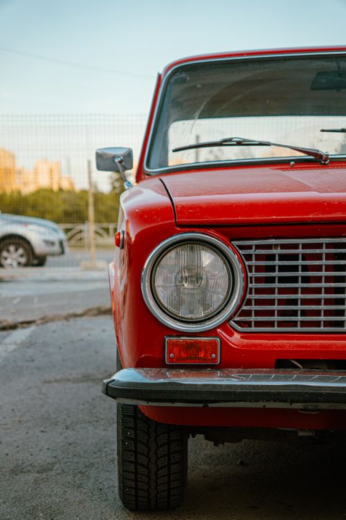 Free Front view of a vintage red car parked outdoors in an urban environment, captured during daytime. Stock Photo