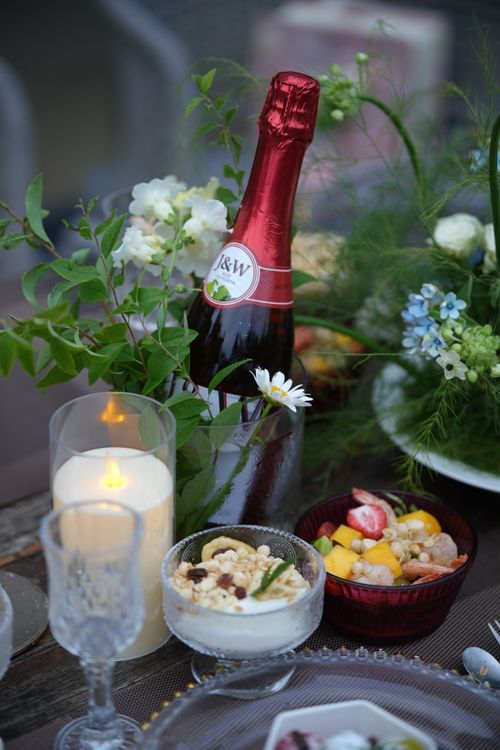 Free Charming table setting with sparkling wine, candles, and floral decor for an outdoor dining experience. Stock Photo