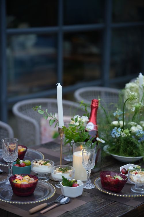 Free A beautifully arranged outdoor dining table with a candle and floral centerpiece, featuring delicious desserts and drinks. Stock Photo