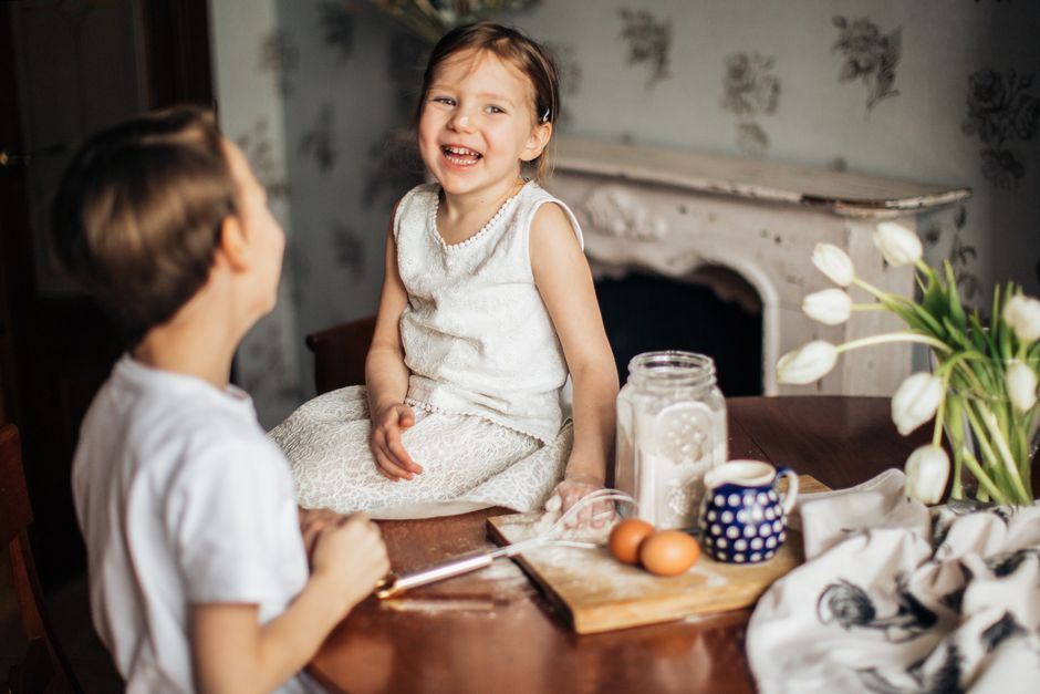 Two happy children enjoying a fun baking session at home, making memories together.