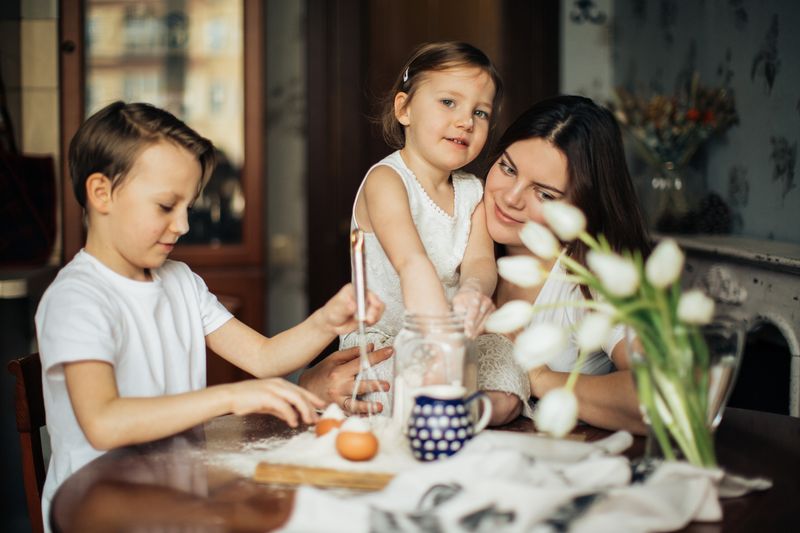 A joyful family moment with a mother and her children baking together indoors.
