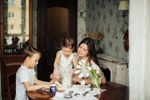 Photo of Woman Sitting Near the Table With Her Children
