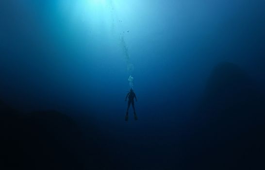 A lone scuba diver explores the deep, serene blue waters of Antalya, Türkiye.