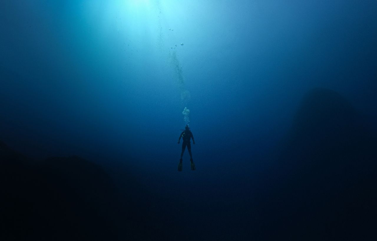 a lone scuba diver explores the deep serene blue waters of antalya t r