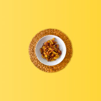 Delicious crispy fried potatoes in a bowl on a vibrant yellow background.