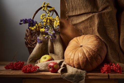 Free A cozy autumn still life featuring a pumpkin, apples, flowers, and burlap on a wooden table. Stock Photo