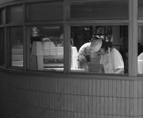 Free Monochrome image of bakers at work in a kitchen viewed through a window. Stock Photo