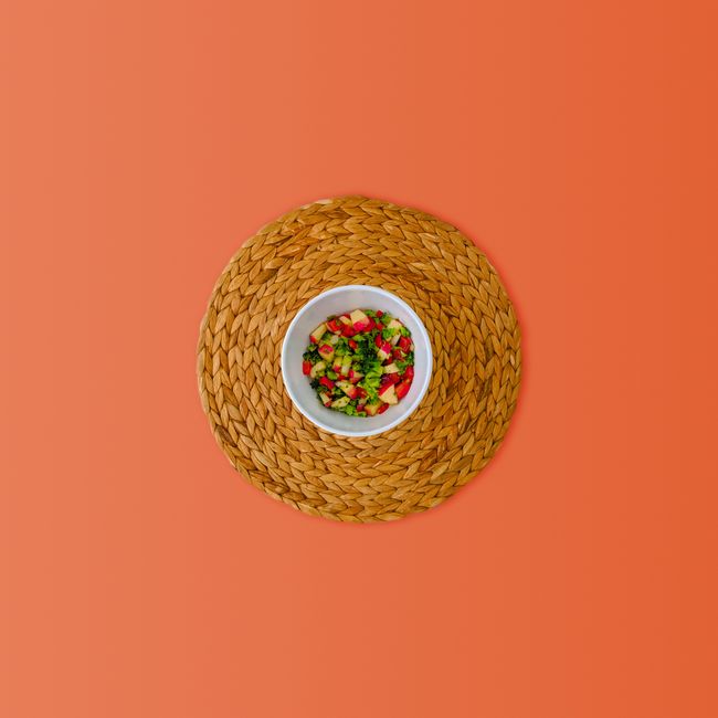 A glass bowl of diced red delicious apple salad with celery, halved red grapes, and chopped walnuts coated in a creamy dressing.