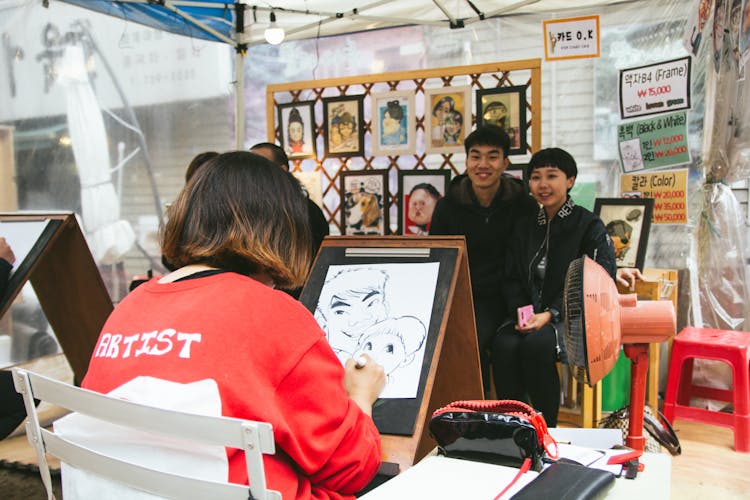 Artist Drawing Caricature Of Smiling Couple