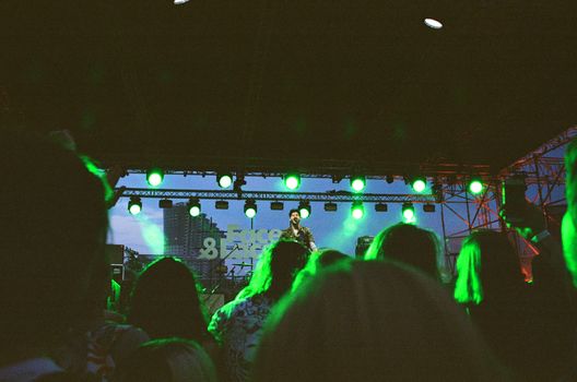 A vibrant live performance by a music band in Moscow with green stage lights, engaging a large audience at night.