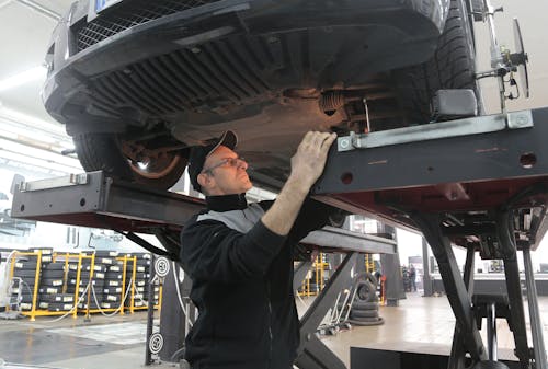 Free Man in Black Jacket Standing Under the Vehicle Stock Photo