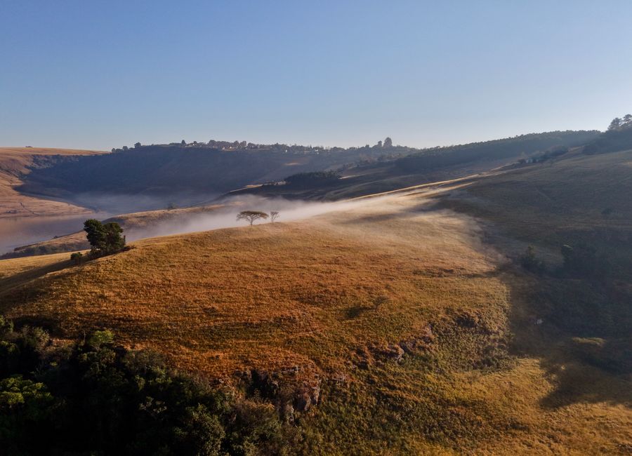 A serene aerial view of mist-covered hills in the Free State, South Africa, at sunrise.