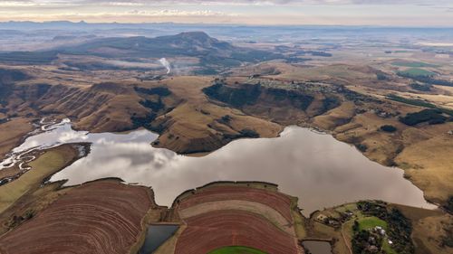 Free A stunning aerial shot showcasing the diverse terrain and serene lake of South Africa. Stock Photo