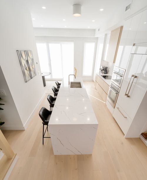 Free Bright and airy modern minimalist kitchen featuring a sleek marble island and black bar stools. Stock Photo