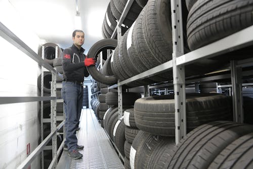 Man in Black Jacket Standing Beside Black Tires