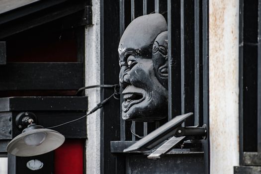 Close-up of a traditional Japanese mask sculpture on a building in Nikkō, Japan.