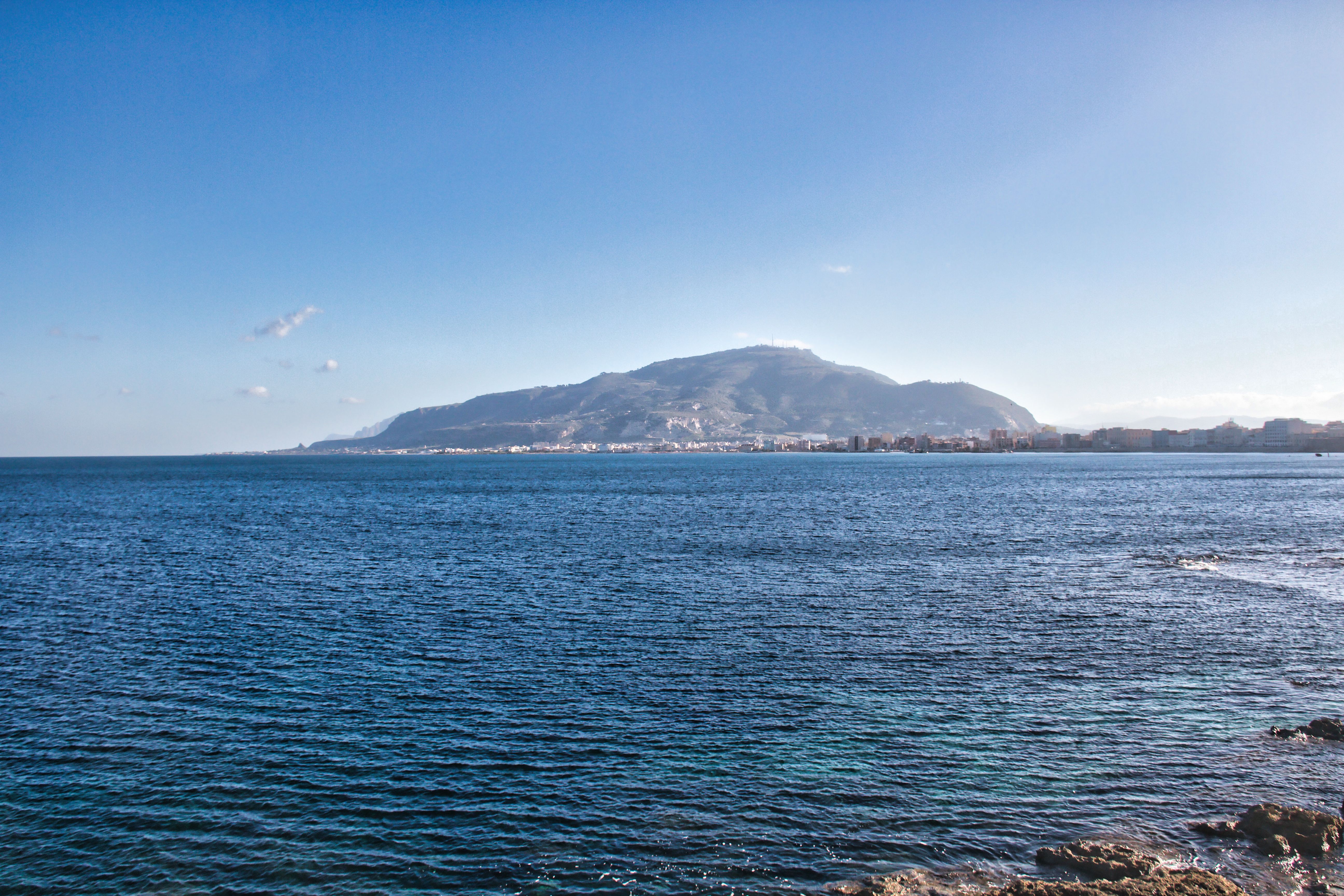 Panoramic view of Trapani coast with Mount Erice in the background under a clear blue sky.