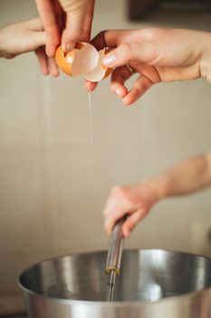 Hands cracking eggs into a bowl with a whisk, perfect for culinary themes.