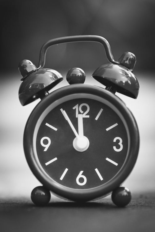 Free Close-up of a classic vintage alarm clock showing 12 o'clock in black and white. Stock Photo