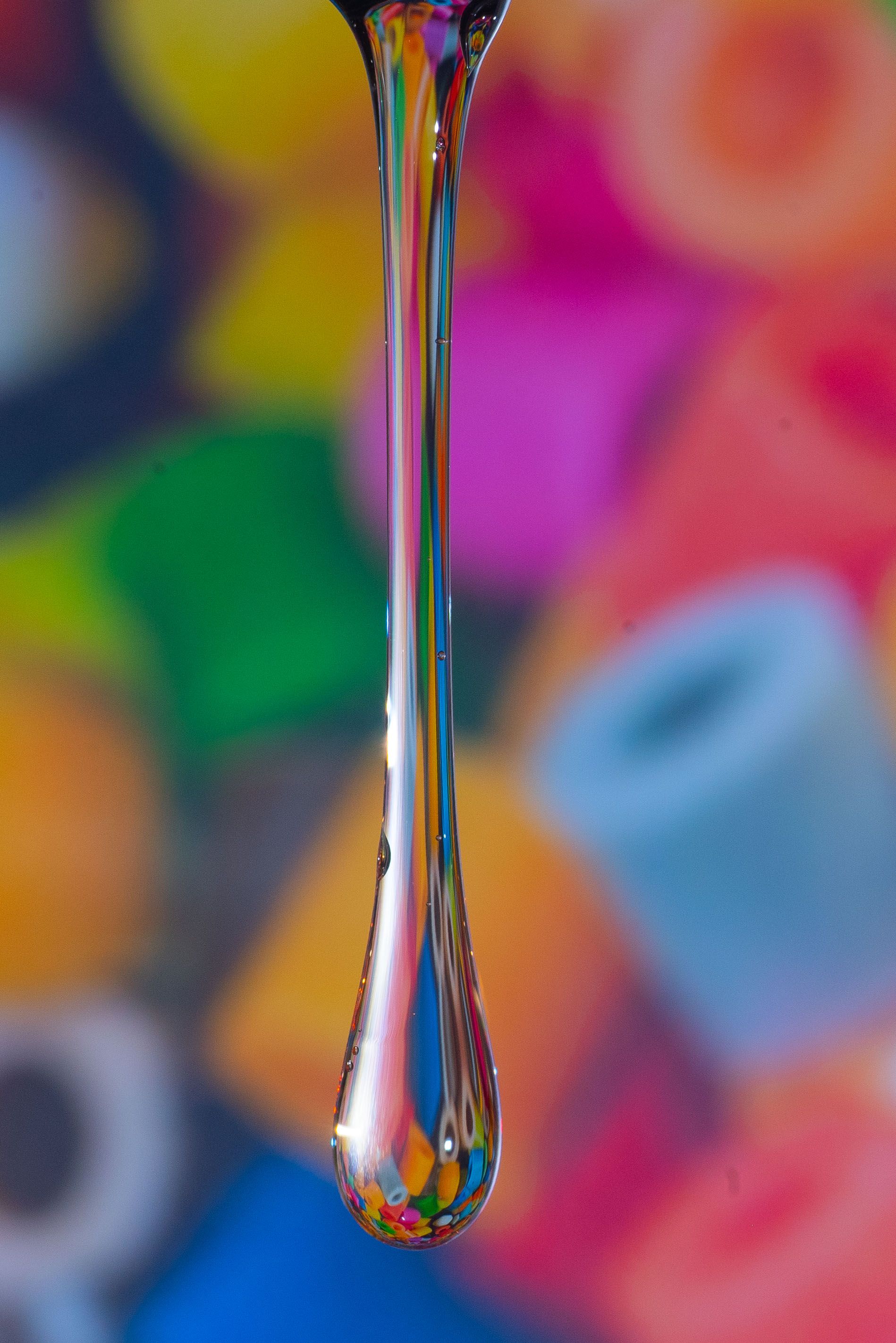Vibrant macro photo of a liquid drop with colorful blurred background.