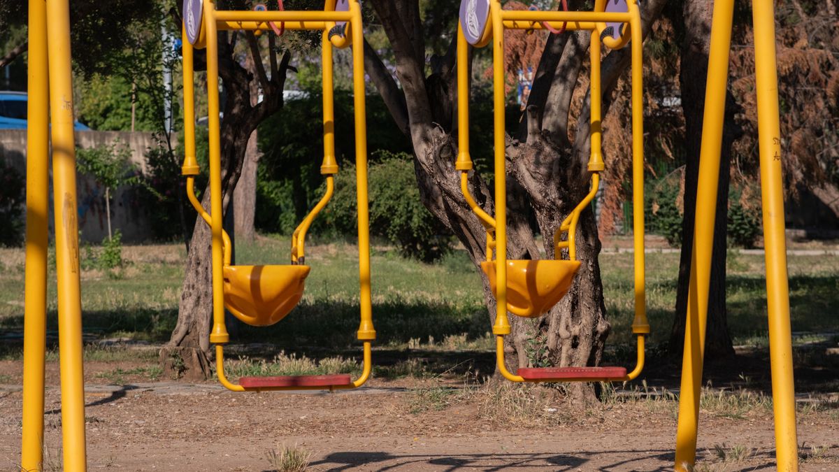 Two bright yellow and red swings in a quiet park in İzmir, Türkiye.
