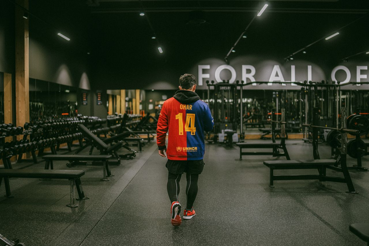 man wearing a colorful jersey walks through a modern well equipped gym