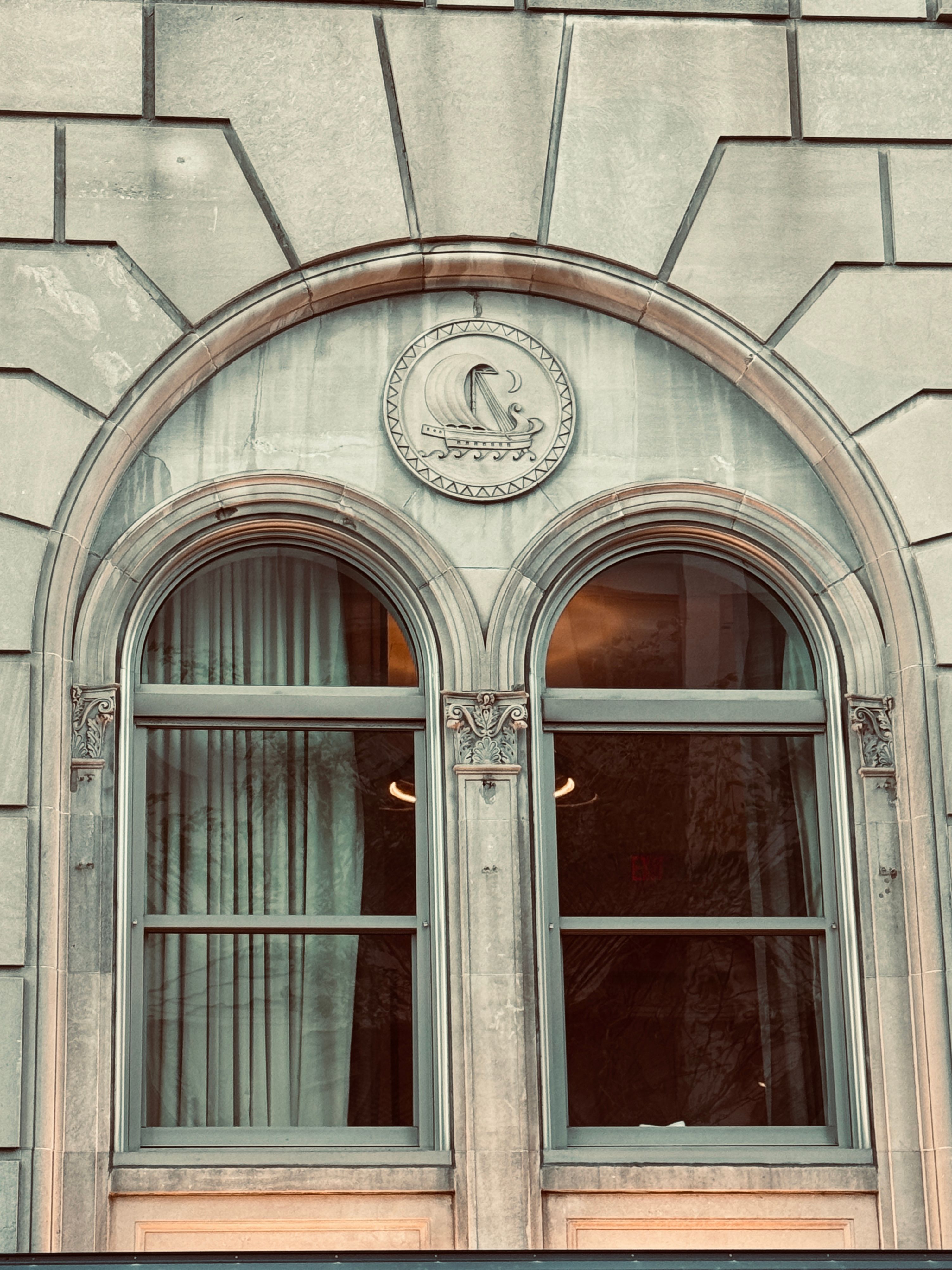 An elegant arched window with stone ornamentation on a historic building facade in Boston, MA.